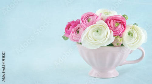Ranunculus flowers in a pink cup with copy space