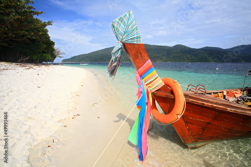 Long tail wooden boat with colorful ribbons on beach photo