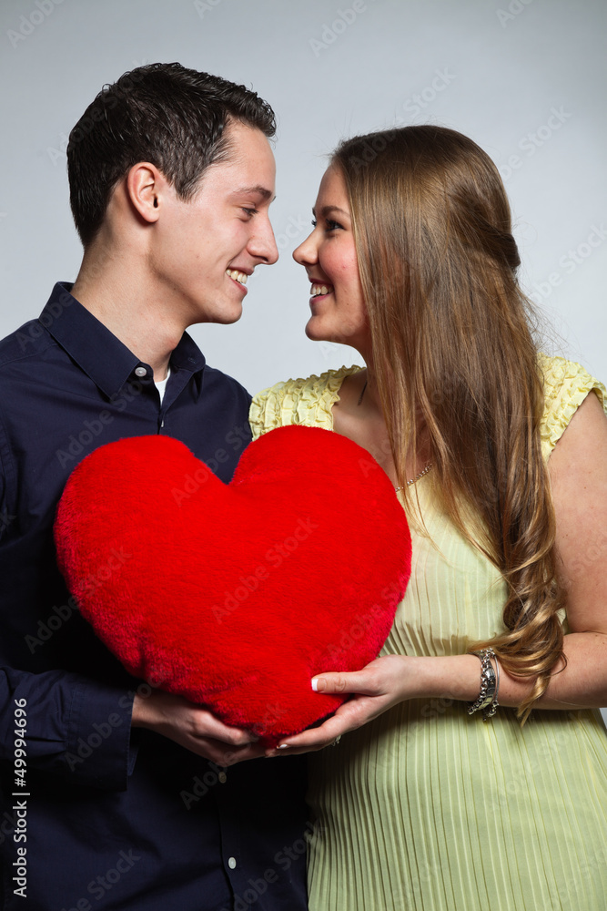 Happy young romantic couple holding red heart. Studio shot. Happy young romantic couple holding red heart. Studio shot.