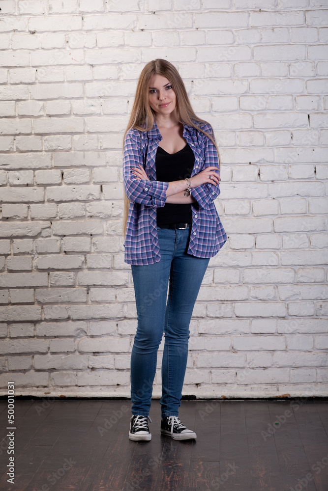Girl posing in studio against a white brick wall Girl posing in studio against a white brick wall