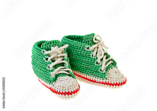 Green crochet baby booties with red line isolated on white