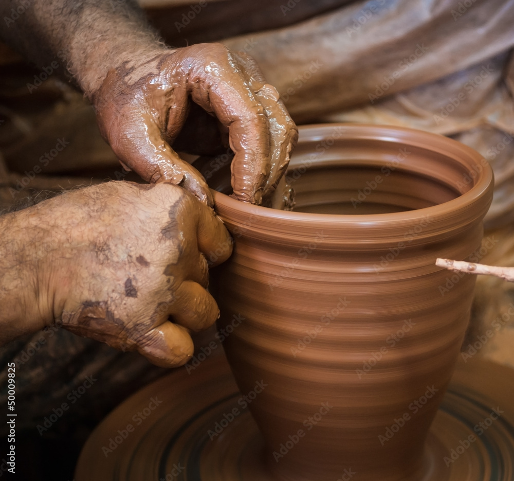Potter hands making in clay on pottery wheel