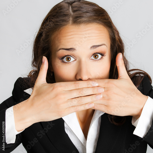 Business woman covering mouth, over gray