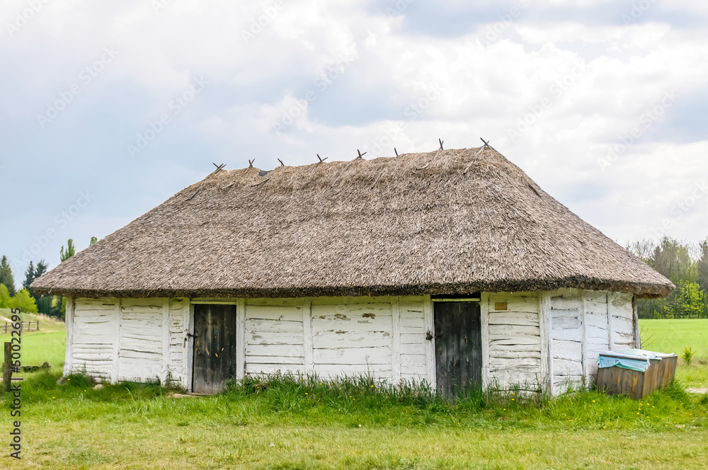 A typical antique Ukrainian wooden country house or farm with a thatch roof, in the countryside near Kiev	