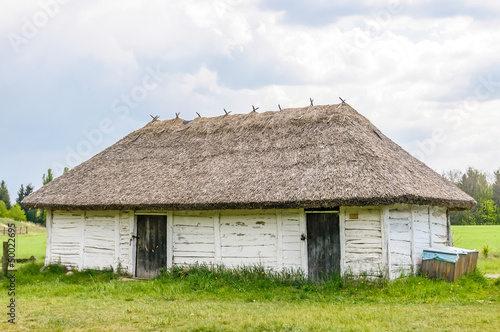 A typical antique Ukrainian wooden country house or farm with a thatch roof, in the countryside near Kiev  © Maxal Tamor
