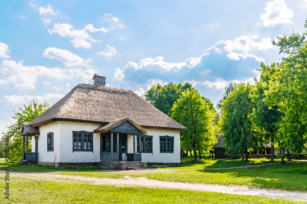 A typical antique Ukrainian country house with a thatch roof, in the countryside near Kiev A typical antique Ukrainian country house with a thatch roof, in the countryside near Kiev