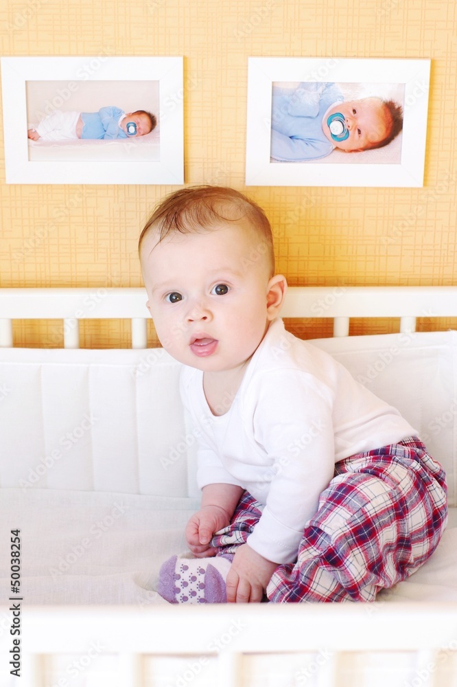 Five-months baby sits in white bed Five-months baby sits in white bed