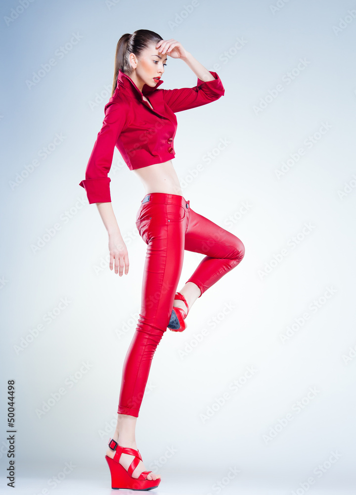 sexy model with slim body dressed in red jumping in the studio