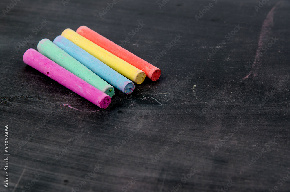 Row of color chalk on a blackboard