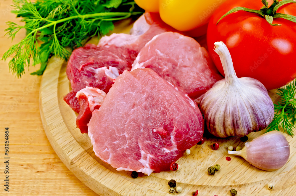 Meat slices on a wooden board with vegetables Meat slices on a wooden board with vegetables