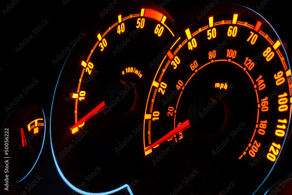 Backlit car dashboard dials glowing at night