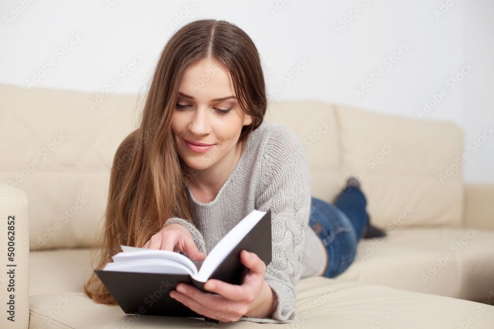 Young woman reading book on sofa Young woman reading book on sofa