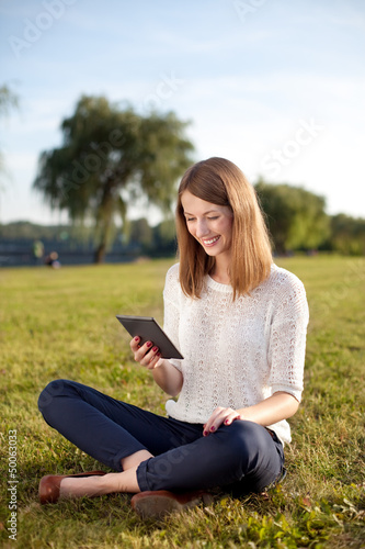 Young woman reading e-book outdoor