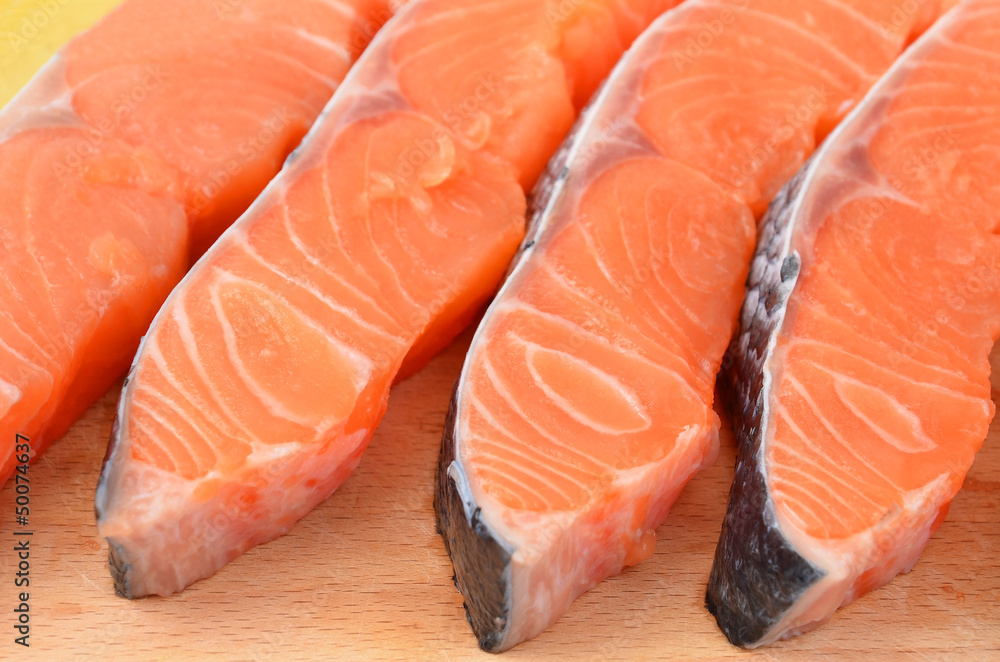 Fresh salmon steak slice on wooden background, DOF