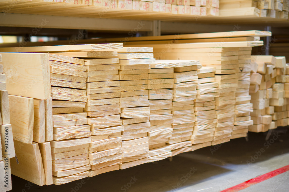 Lumber boards and beams of different sizes lie on racks and pall Lumber boards and beams of different sizes lie on racks and pall