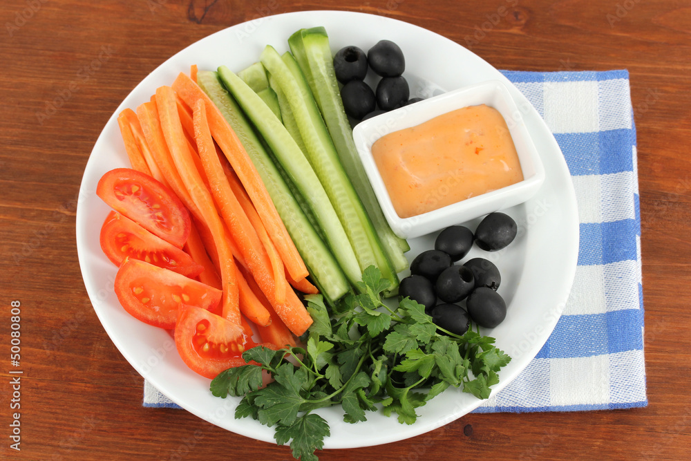 Assorted raw vegetables sticks in plate on wooden table close Assorted raw vegetables sticks in plate on wooden table close