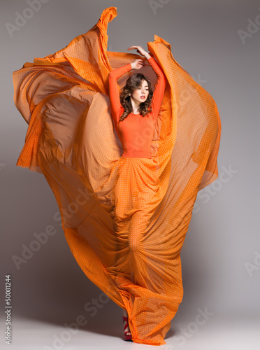 beautiful woman in long orange dress posing in the studio