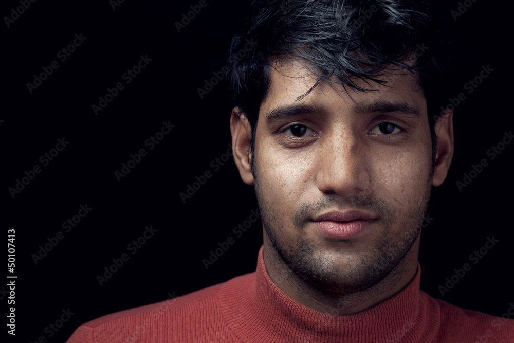 Fototapeta premium Portrait of young Indian man over dark