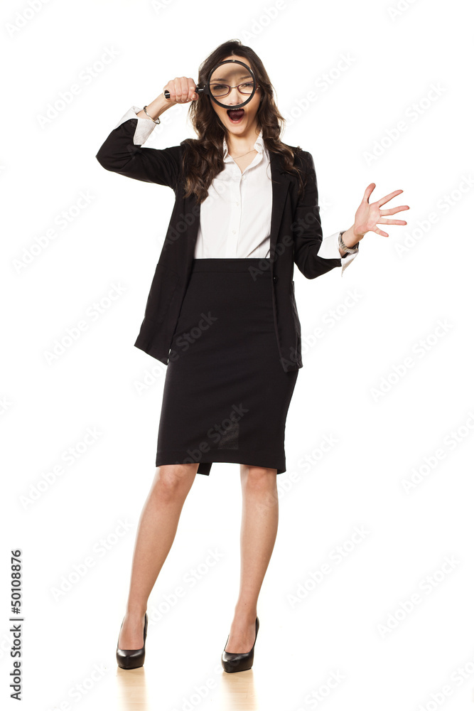 dissatisfied and angry business woman looking through a magnifyi dissatisfied and angry business woman looking through a magnifyi