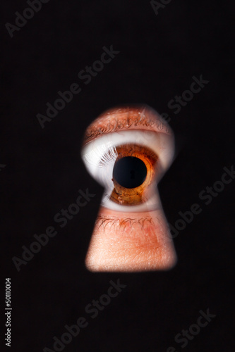 Eye looking through a keyhole