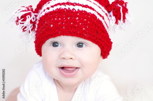 Portrait of the smiling baby in a red knitted hat