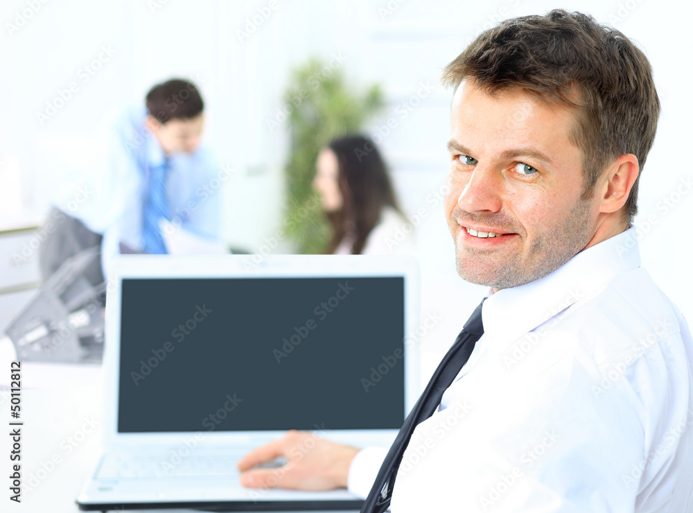 Business man sitting at his desk in the office with a laptop Business man sitting at his desk in the office with a laptop
