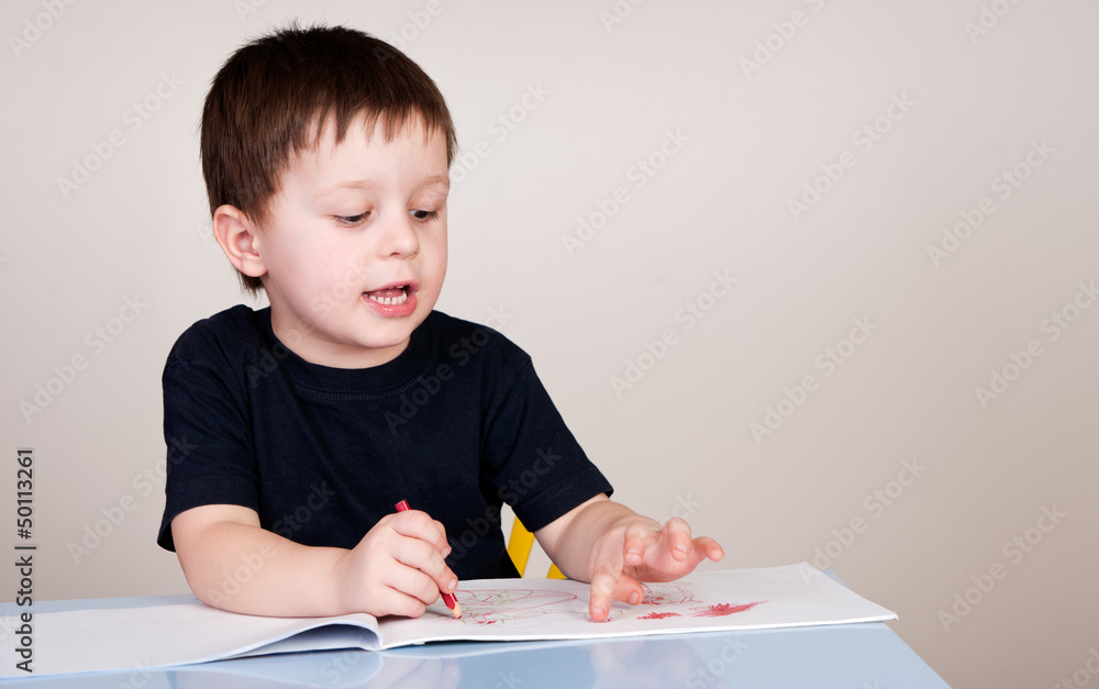 Boy drawing with coloured pencils on sheets of the block Boy drawing with coloured pencils on sheets of the block