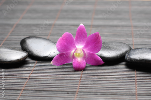 Pink orchid and zen Stones on bamboo stick straw mat