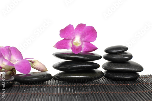 pink orchid with black pebble on bamboo stick straw mat