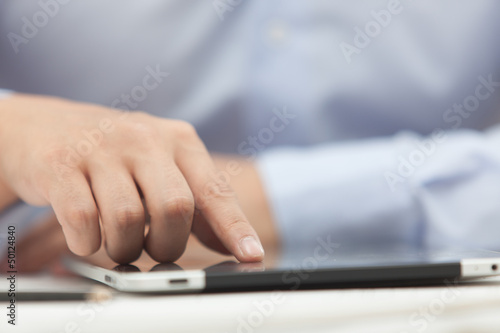 Hands of the man in the blue shirt are holding a tablet computer