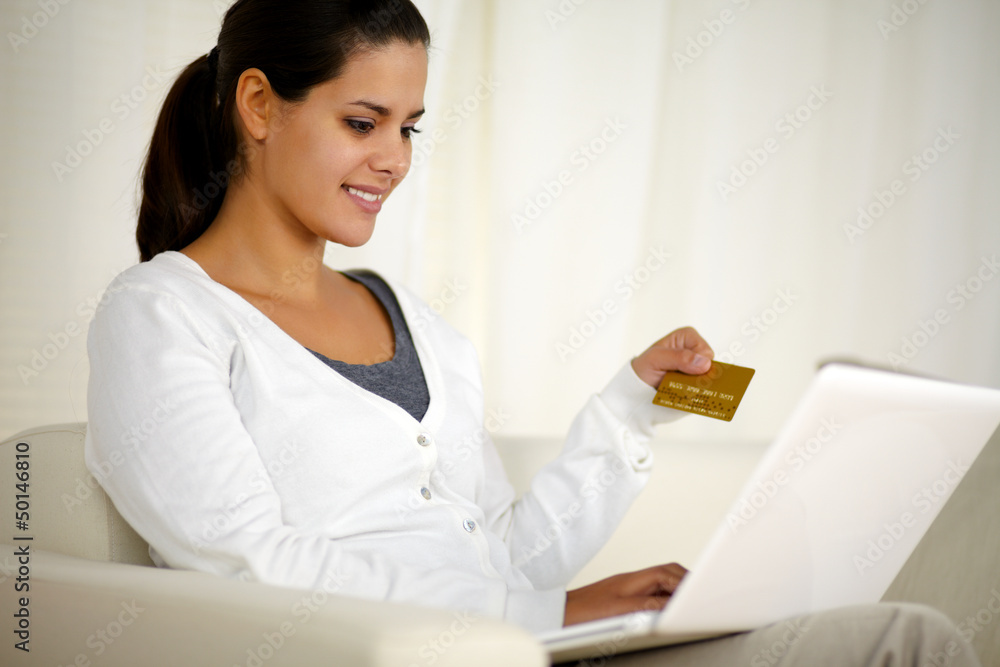 Charming young woman holding a gold credit card Charming young woman holding a gold credit card