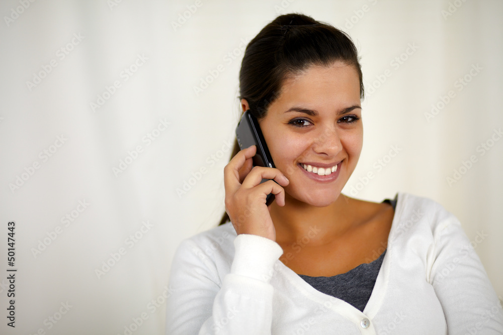 Young woman conversing on mobile phone looking you Young woman conversing on mobile phone looking you