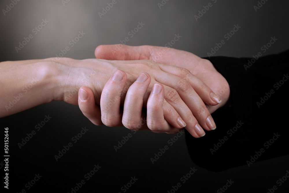 Priest holding woman hand, on black background