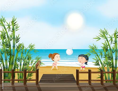 Two young girls playing volleyball at the beach