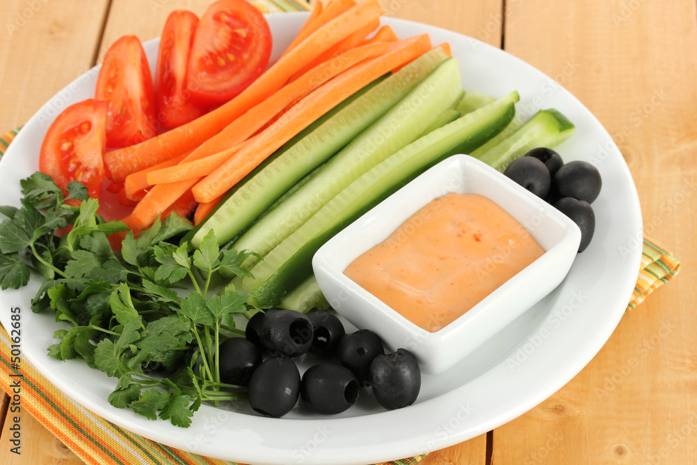Assorted raw vegetables sticks in plate on wooden table close