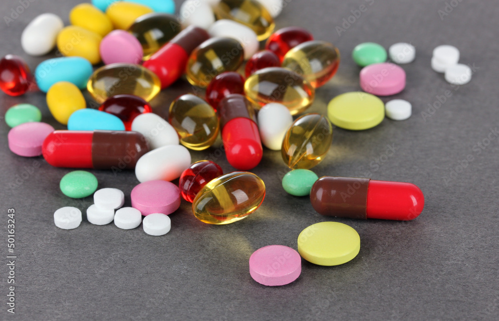 Assortment of pills, tablets and capsules on grey background Assortment of pills, tablets and capsules on grey background