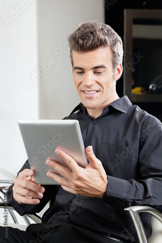 Male Client Using Digital Tablet In Salon