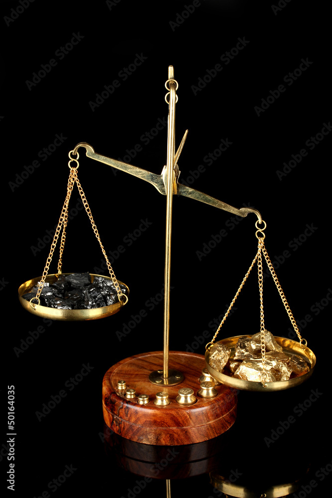 Gold and coal on scales on dark grey background Gold and coal on scales on dark grey background