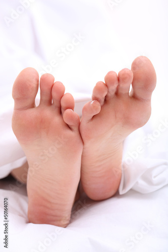 Beautiful feet of a young woman lying in bed close up © Africa Studio