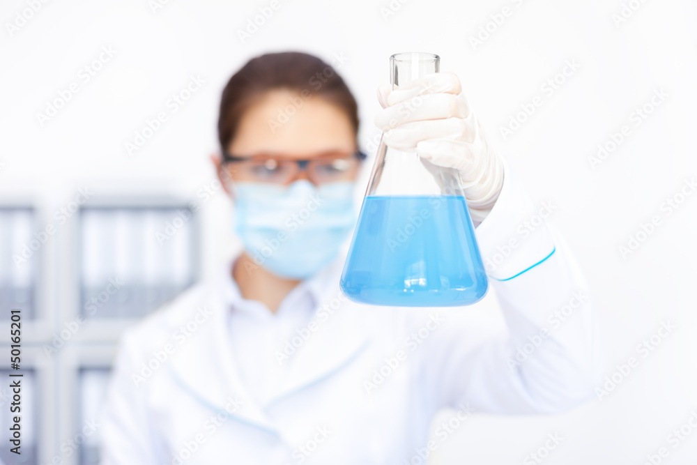 female researcher observing liquid in flask female researcher observing liquid in flask