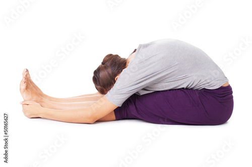 Young woman doing yoga asana seated forward bend Paschimottanasa photo