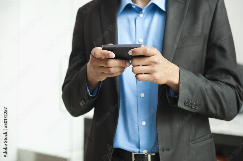 Black businessman text messaging on cell phone Black businessman text messaging on cell phone