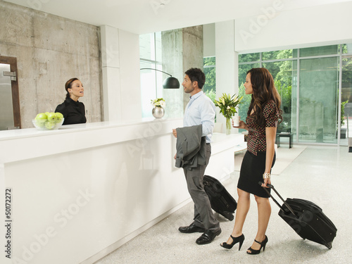 Business people arriving at hotel reception area photo
