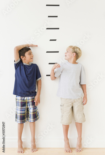 Boys measuring themselves against marks on wall photo