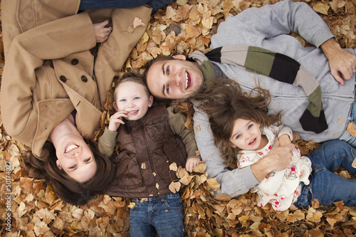 Caucasian family laying in autumn leaves photo