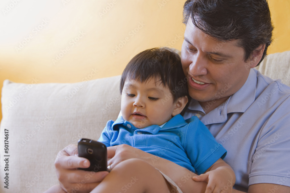 Hispanic father showing cell phone to his son Hispanic father showing cell phone to his son