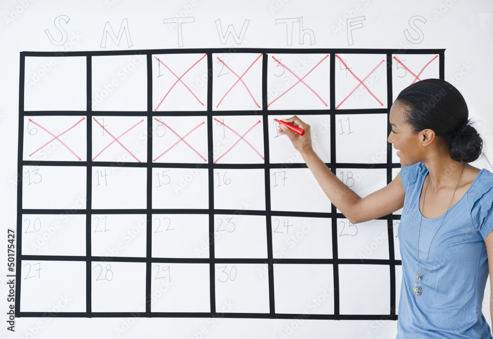 Black woman marking the days off calendar Black woman marking the days off calendar
