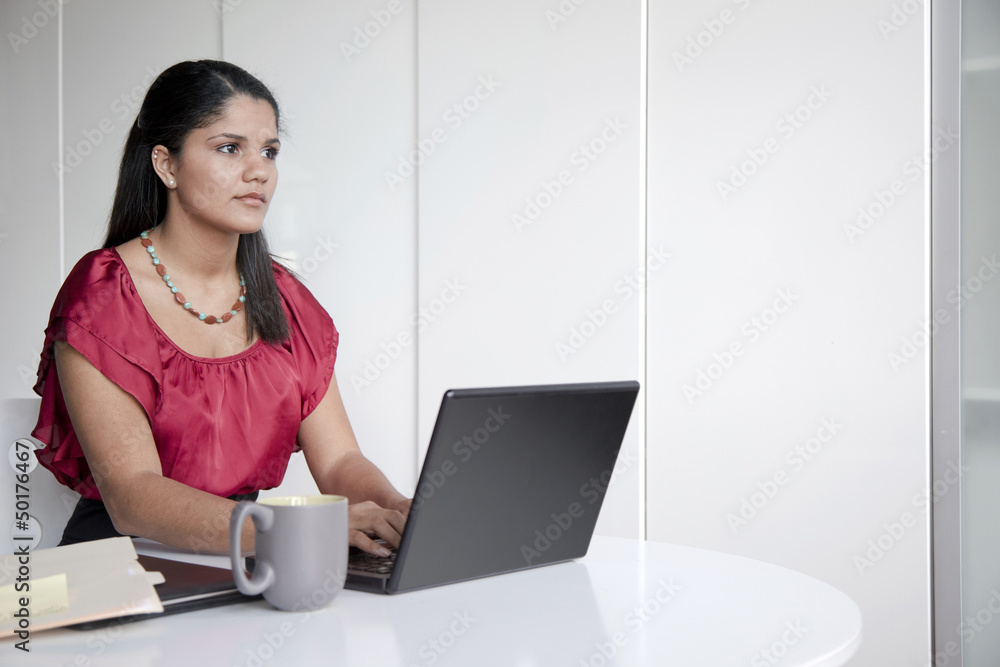 Hispanic businesswoman typing on laptop in office Hispanic businesswoman typing on laptop in office