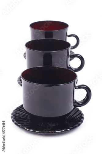 a series of black glass cups and saucers isolated
