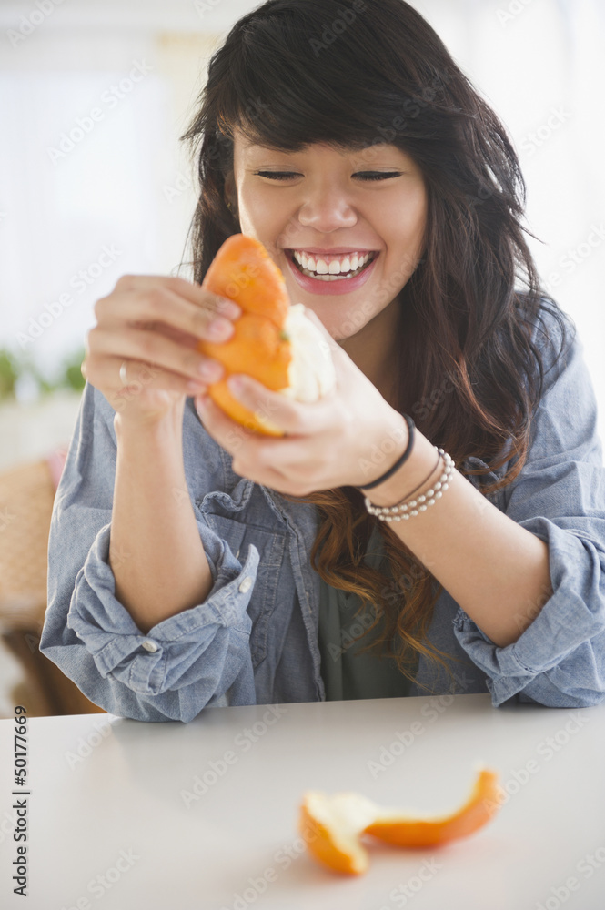 Pacific Islander woman peeling an orange Pacific Islander woman peeling an orange